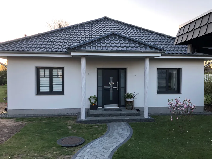 Bungalow mit weißer Fassade, Säulen und überdachtem Hauseingang